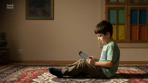 پسر بچه ای که در یک اتاق، روی قالی ایرانی با یک تبلت در دست نشسته است.
