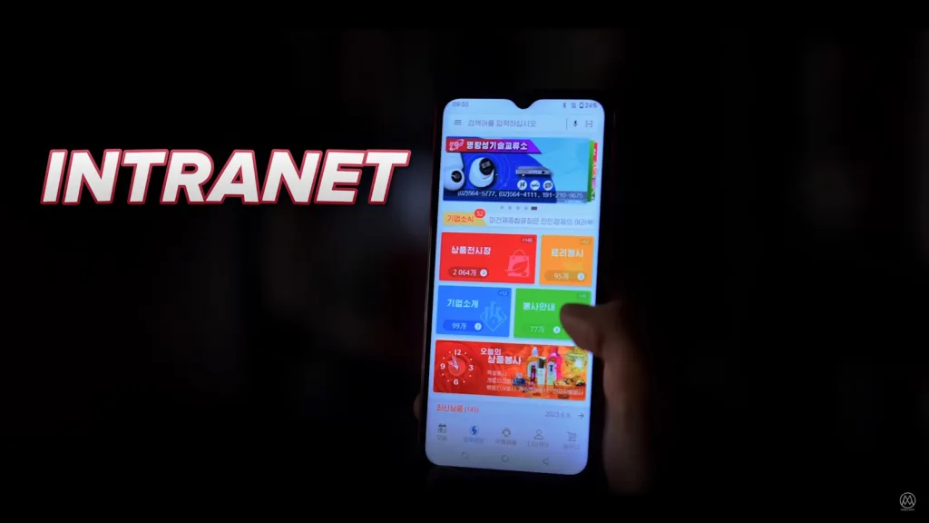 یک گوشی موبایل در حال نمایش صفحه‌ای با عنوان “INTRANET” به رنگ قرمز و سفید است. صفحه گوشی شامل بخش‌های رنگارنگ و مختلفی مانند اخبار شرکت، بازار محصولات، و اطلاعیه‌ها است که با رنگ‌های متنوع دسته‌بندی شده‌اند.