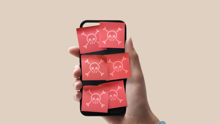 یک گوشی هوشمند در دست در حالی که روی صفحه‌نمایش آن، کاغذهای چسبان قرمز با طرح اسکلت کارتونی چسبیده است. ؛ برچسب‌های قرمز با علامت جمجمه نشان‌دهنده نفوذ بدافزارها، جاسوس‌افزارها و تهدیدات امنیتی متعدد روی یک تلفن هوشمند هستند. تصویر مفهوم Android phone hacked, malware infection و ضرورت اجرای checklis نجات و ایمن‌سازی گوشی اندروید پس از نفوذ را منتقل می‌کند