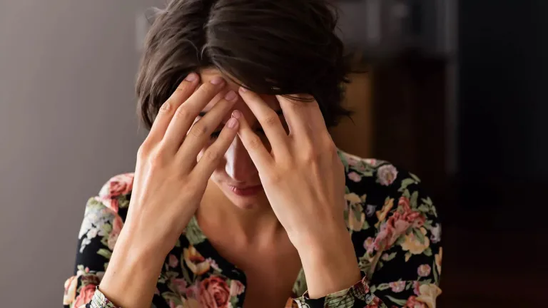 تصویری از خانمی که دست‌های خود را روی صورت و پیشانی گذاشته، نمادی از استیصال و ناراحتی