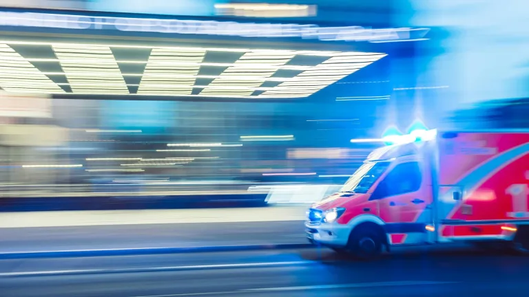 تصویری از یک آمبولانس که با سرعت زیاد از سمت راست وارد کادر می‌شود، نمادی از شرایط اضطرار و بحران