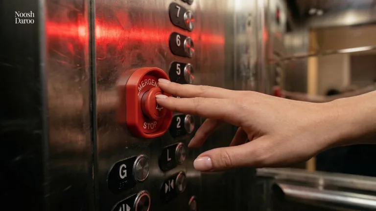 دست یک خانم در حالی که درون آسانسور دارد دکمه هشدار آسانسور را فشار می‌دهد