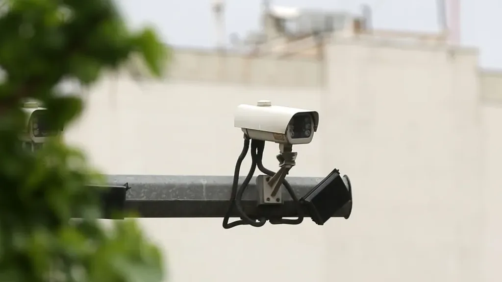 یک دوربین امنیتی به رنگ سفید که روی میله نصب شده است