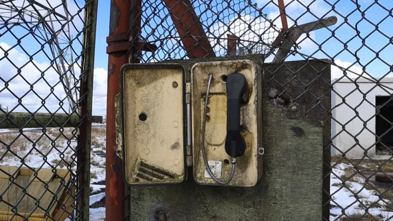 تصویری از یک باجه تلفن قدیمی در کنار یک دکل مخابراتی، نمادی از ارتباطات رادیویی دوران جنگ سرد.