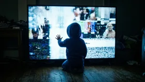 کودکی خردسال در اتاقی تاریک به صفحه روشن و درهم‌ریخته تلویزیون نزدیک شده و آن را لمس می‌کند