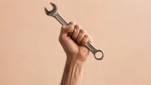 دستِ مشت‌شده‌ای که یک آچار فلزی را محکم گرفته، در نمایی ساده و مینیمال با پس‌زمینه روشن و حال‌وهوای رئال؛ نمادی از جنبش «حق تعمیر».