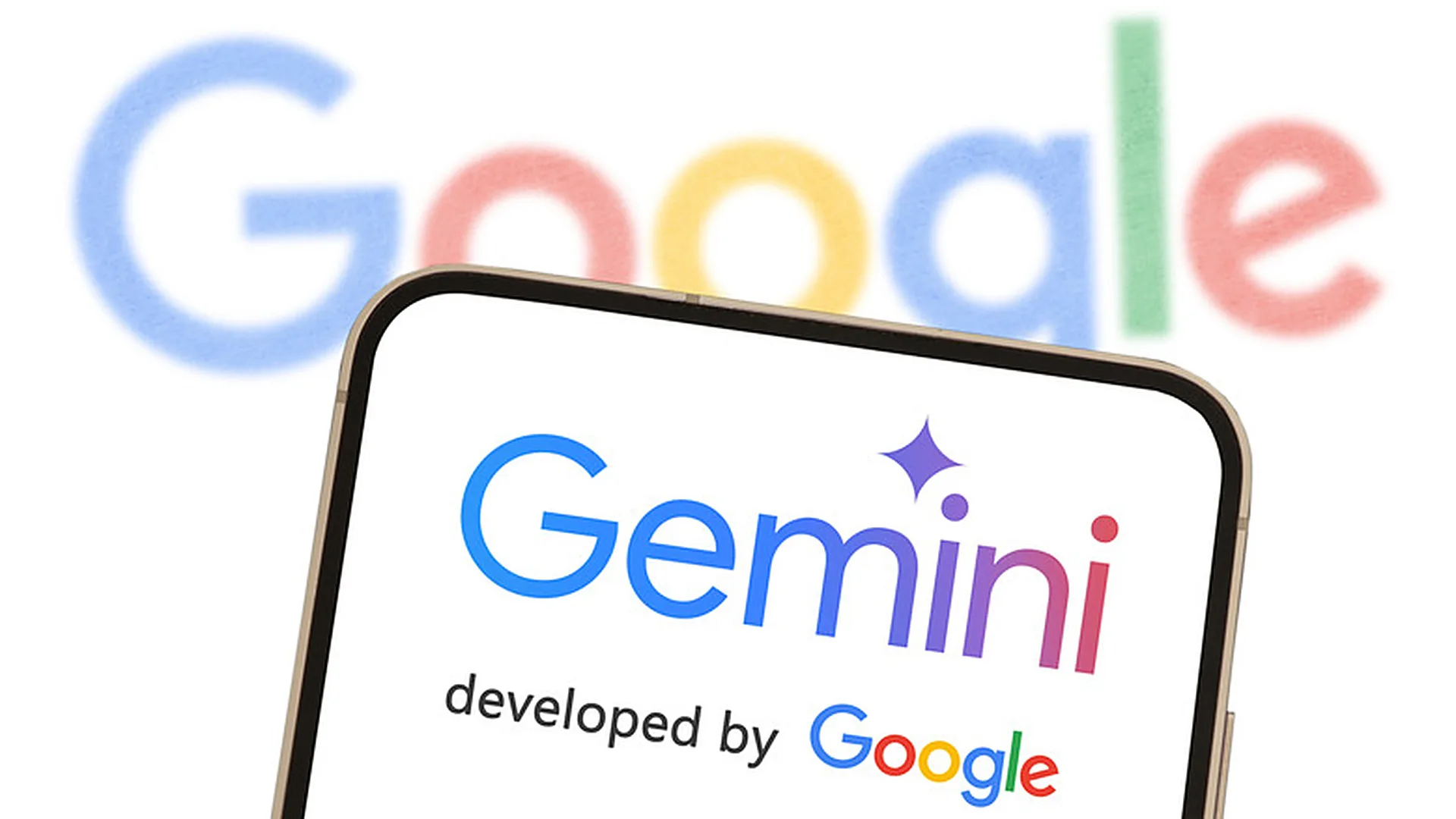 گوشی هوشمندی که لوگوی جمینای و عبارت «developed by Google» را نشان می‌دهد، در برابر لوگوی بزرگ و محوشده‌ی گوگل