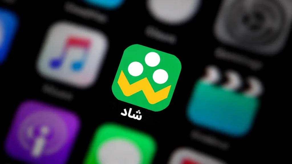 نمای نزدیک از آیکون اپلیکیشن «شاد» روی صفحه گوشی، در میان آیکون‌های محو دیگر.